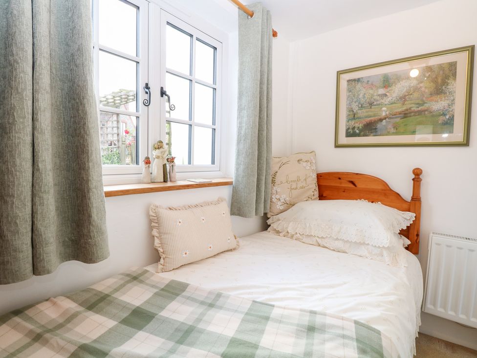 A bedroom with a bed and window at Hollyhedge Cottage in Briston