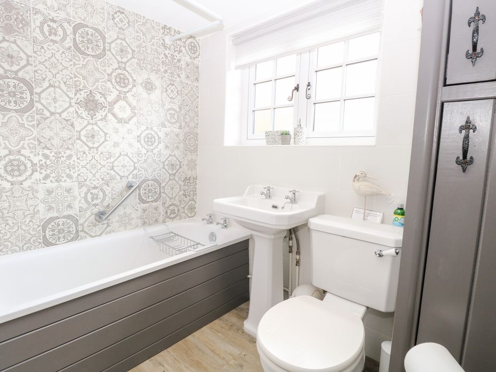 A bathroom with a bathtub and sink at Hollyhedge Cottage in Briston