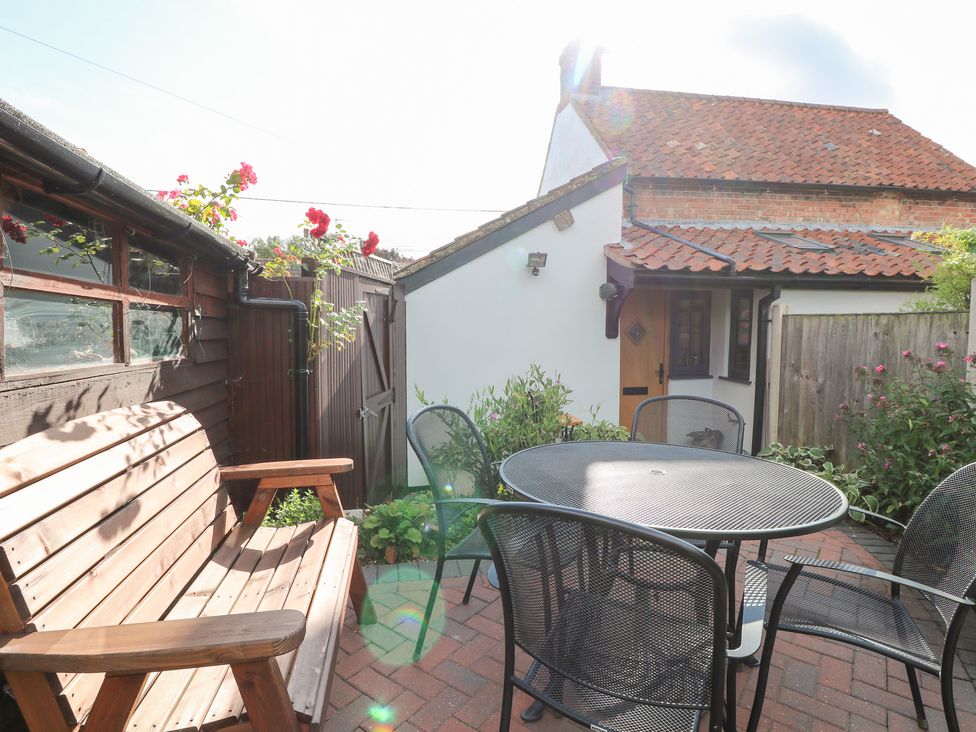 A garden with a table and chairs near a shed at Hollyhedge Cottage in Briston