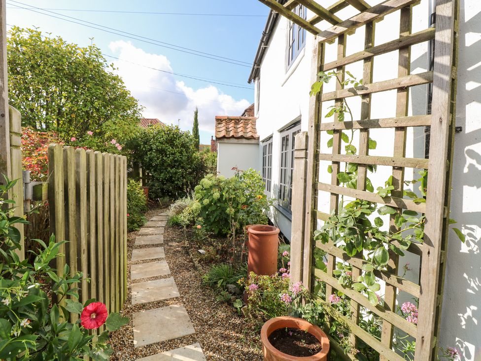 A garden with a pathway and trellis at Hollyhedge Cottage in Briston