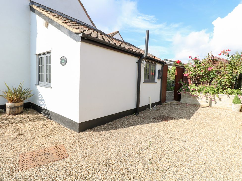 An exterior view of a cottage with a gravel path at Hollyhedge Cottage in Briston