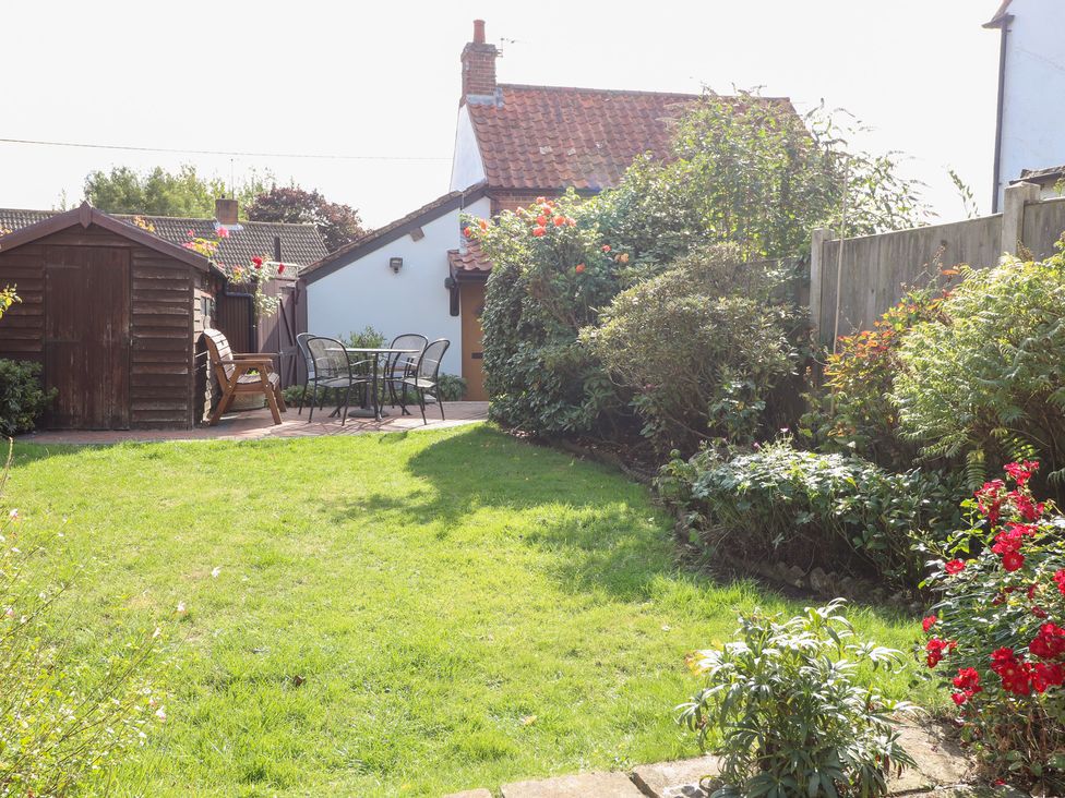 A garden with a shed and seating area at Hollyhedge Cottage in Briston
