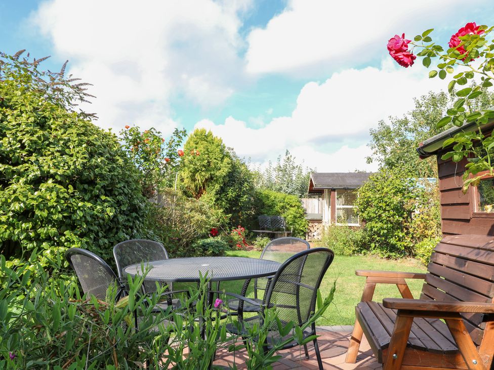 A garden with a table and chairs at Hollyhedge Cottage in Briston
