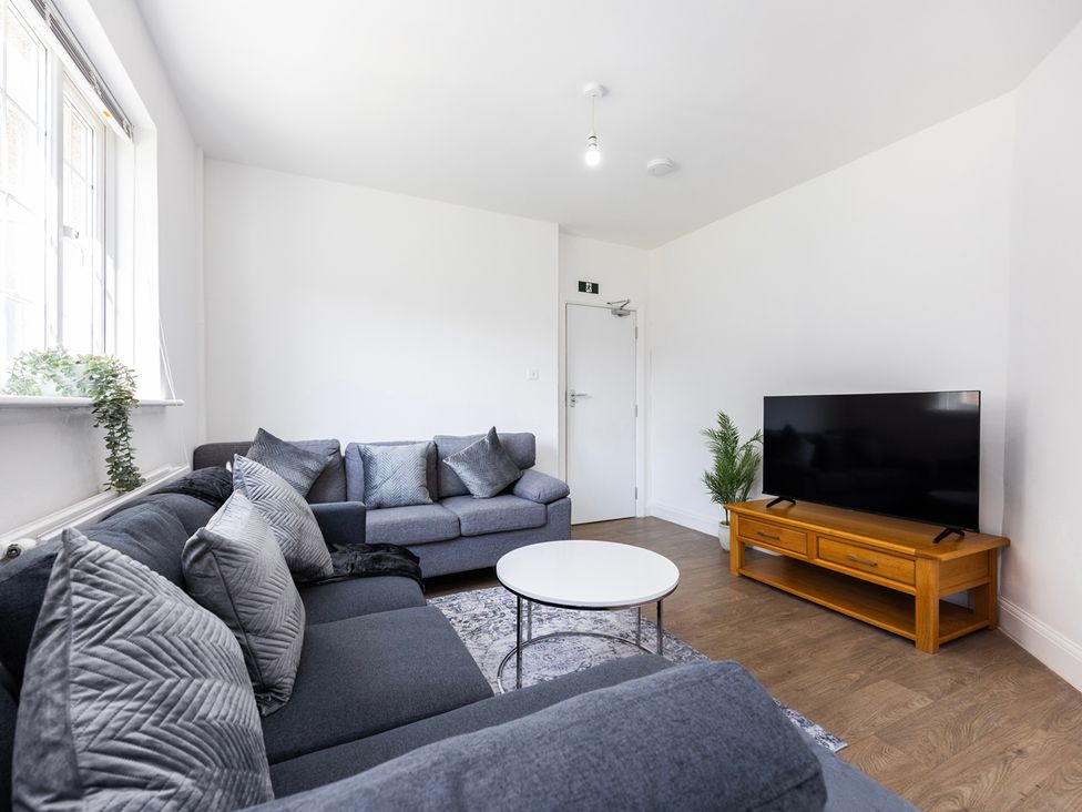 A living room with a sofa and television at House Sleeps 14 with Parking and Garden in East Tilbury