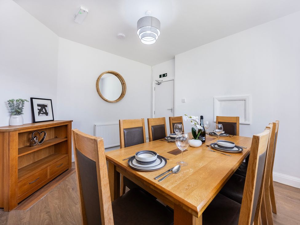 A dining room with a wooden table and chairs at House Sleeps 14 with Parking and Garden East Tilbury