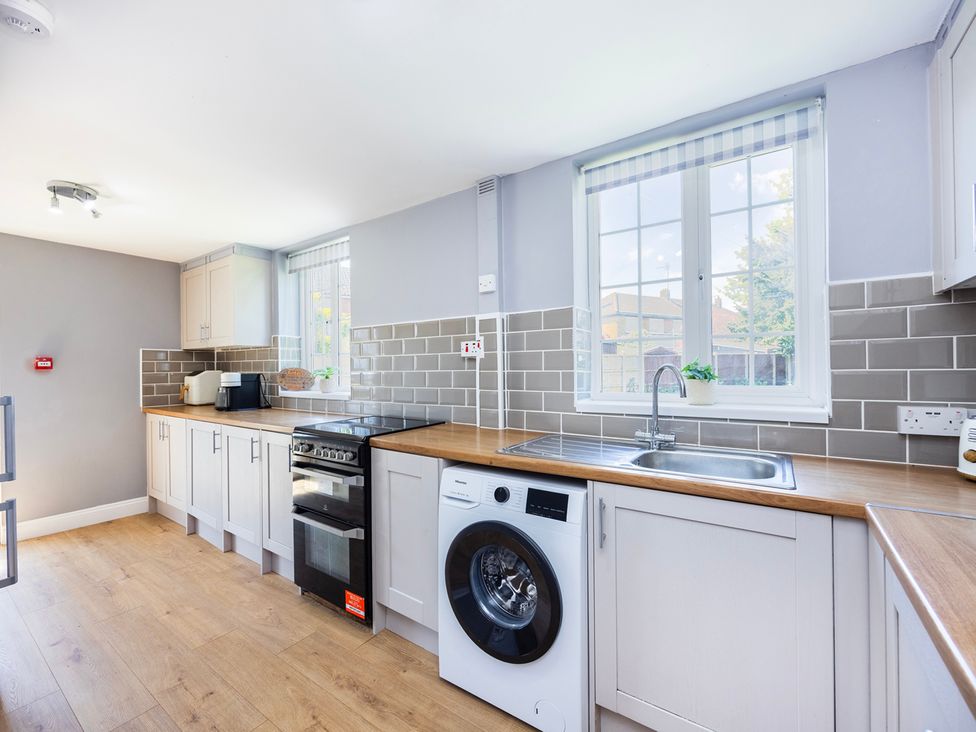 A kitchen with a sink and a washing machine at House Sleeps 14 with Parking and Garden East Tilbury