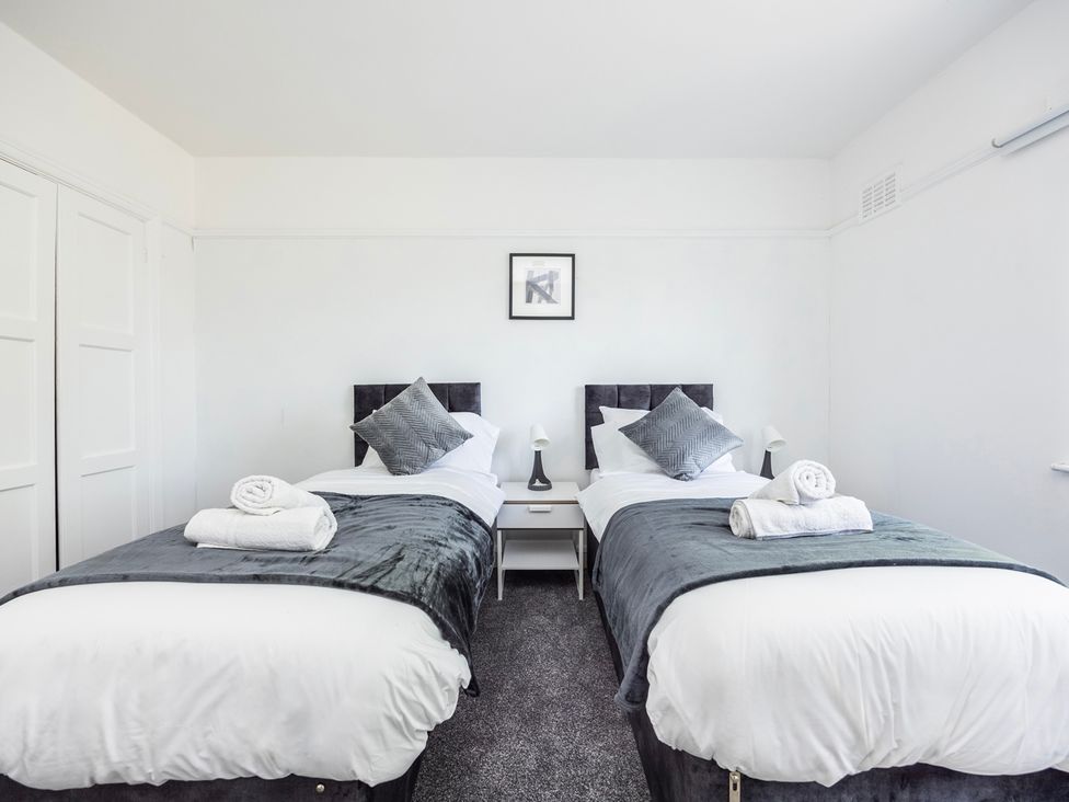 A bedroom with two single beds and bedside tables at House Sleeps 14 with Parking and Garden in East Tilbury