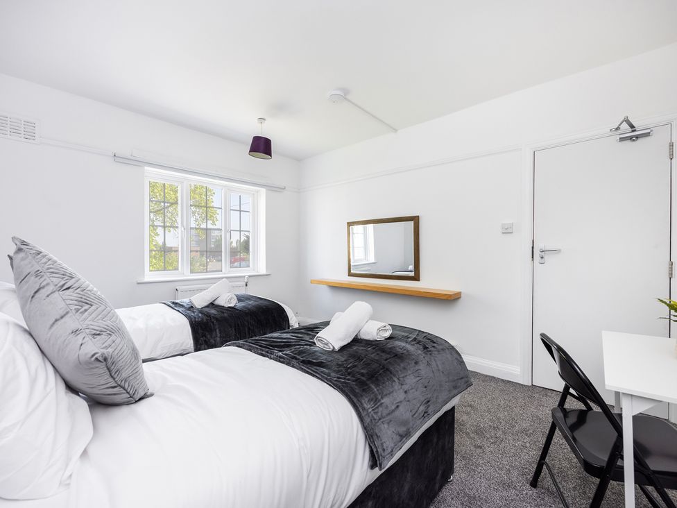 A bedroom with two beds and a mirror at House Sleeps 14 with Parking and Garden in East Tilbury