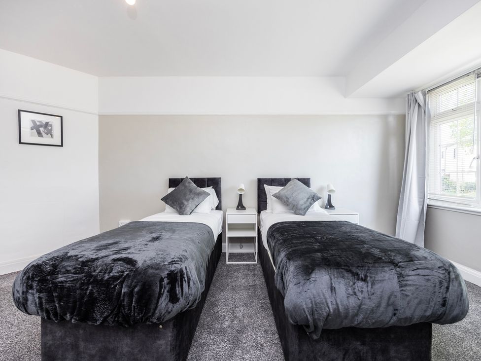 A bedroom with two beds and a nightstand at House Sleeps 14 with Parking and Garden East Tilbury