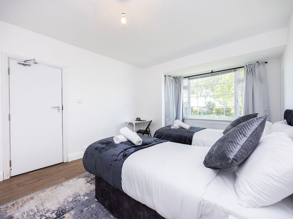 A bedroom with two beds and a table at House Sleeps 14 with Parking and Garden East Tilbury