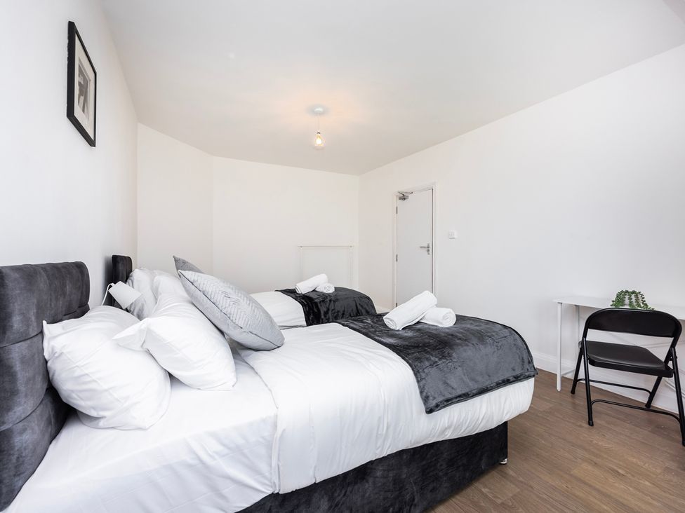 A bedroom with two beds and a small table at House Sleeps 14 with Parking and Garden East Tilbury