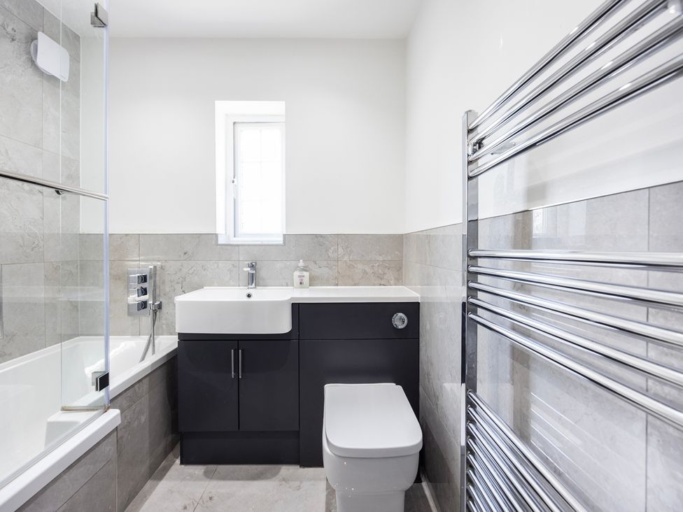 A bathroom with a bathtub, toilet, sink, and radiator at House Sleeps 14 with Parking and Garden, East Tilbury