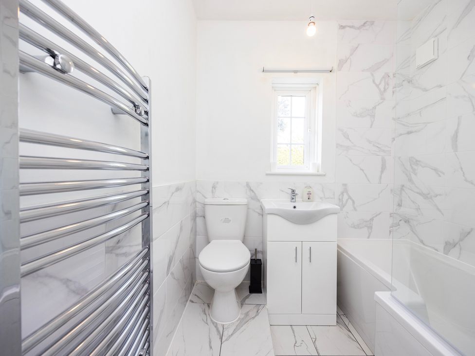 A bathroom with a toilet, sink, towel radiator, and bathtub at House Sleeps 14 with Parking and Garden, East Tilbury