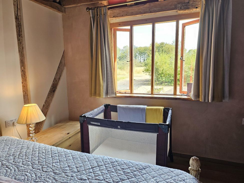 A bedroom with a crib and window at Pet Friendly 3Bed Barn Sleeps 7 Parking Garden in Westhall near Halesworth