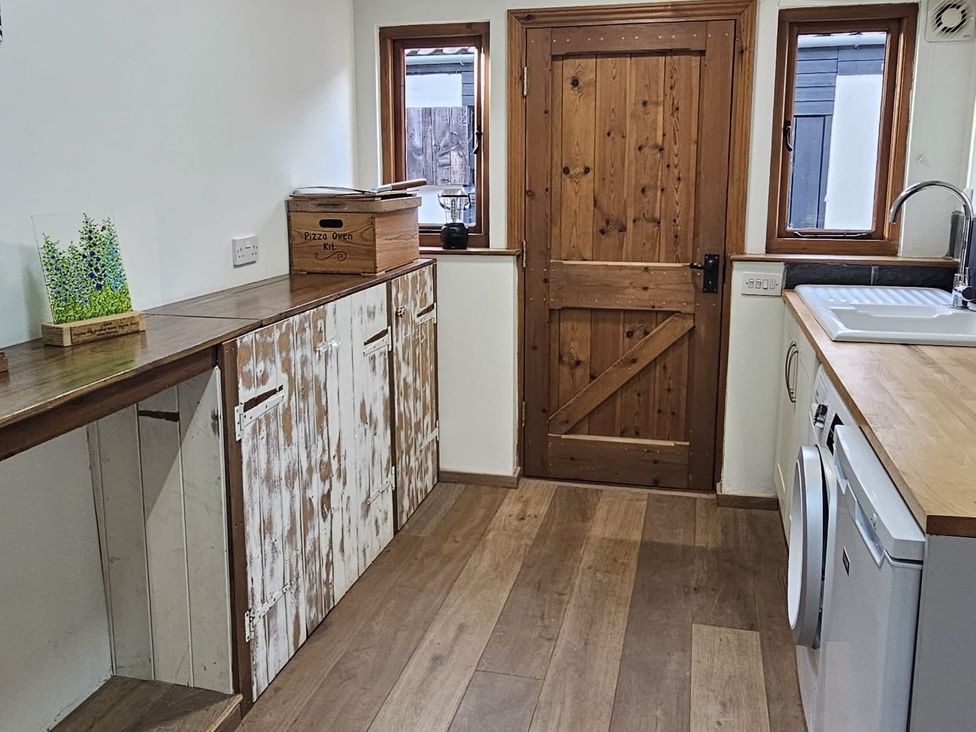 A kitchen with wooden cabinets and a door at Pet Friendly 3Bed Barn Sleeps 7 Parking Garden Westhall near Halesworth