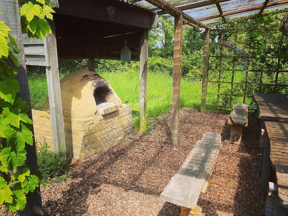 An outdoor area with an oven, wooden benches, and a table at Pet Friendly 3Bed Barn Sleeps 7 Parking Garden in Westhall near Halesworth