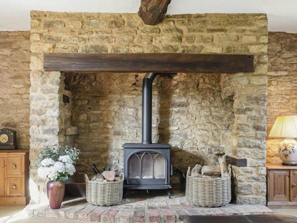A living room with a stove and wooden furniture at 17th Century Farmhouse Near Silverstone Circuit Tiffield