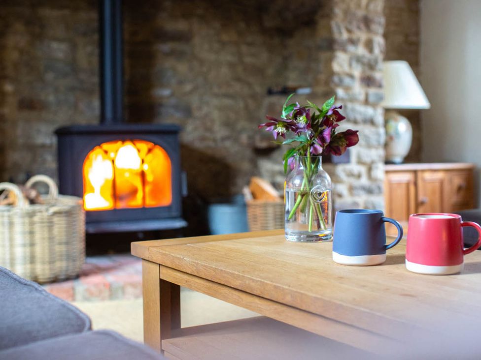 A living room with a fireplace and mugs on the table at 17th Century Farmhouse Near Silverstone Circuit, Tiffield