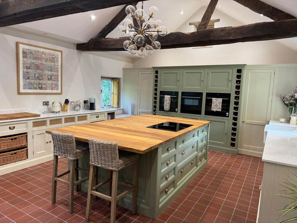 A kitchen with an island, cabinets, and appliances at 17th Century Farmhouse Near Silverstone Circuit, Tiffield