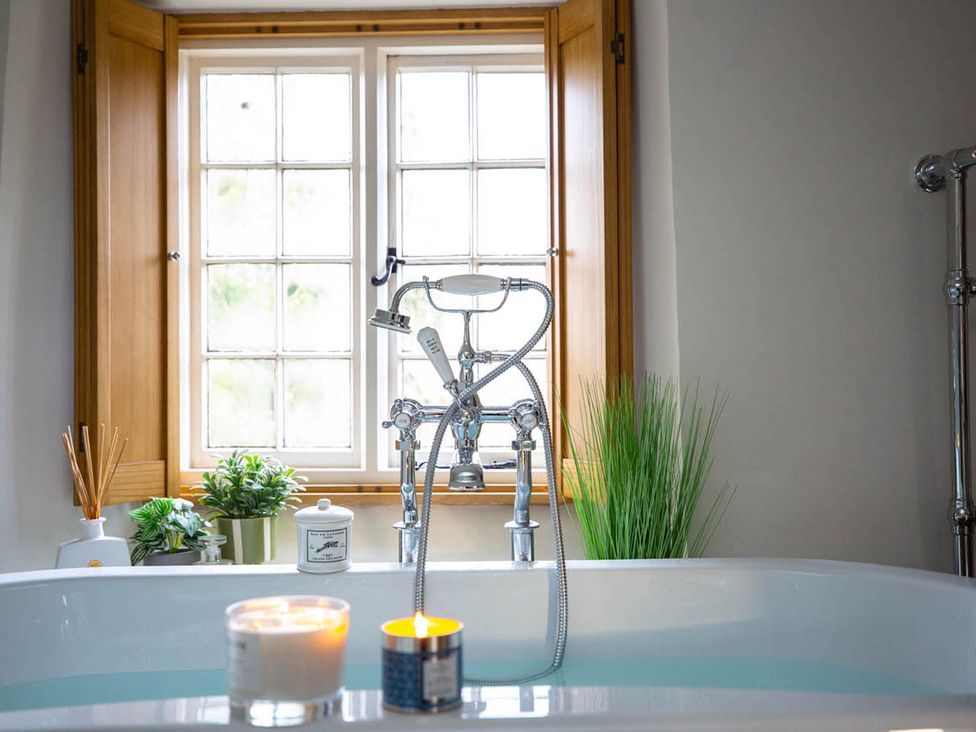 A bathroom with a bathtub and window at 17th Century Farmhouse Near Silverstone Circuit Tiffield