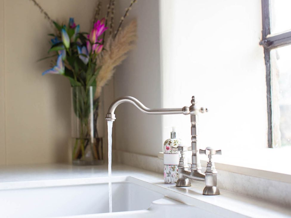 A sink with a faucet and flowers in a vase at 17th Century Farmhouse Near Silverstone Circuit Tiffield
