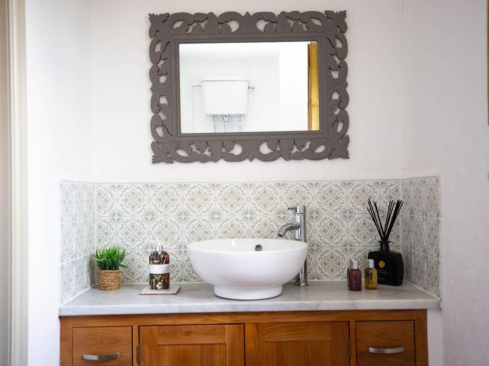 A sink with a mirror above and decorative items at 17th Century Farmhouse Near Silverstone Circuit Tiffield