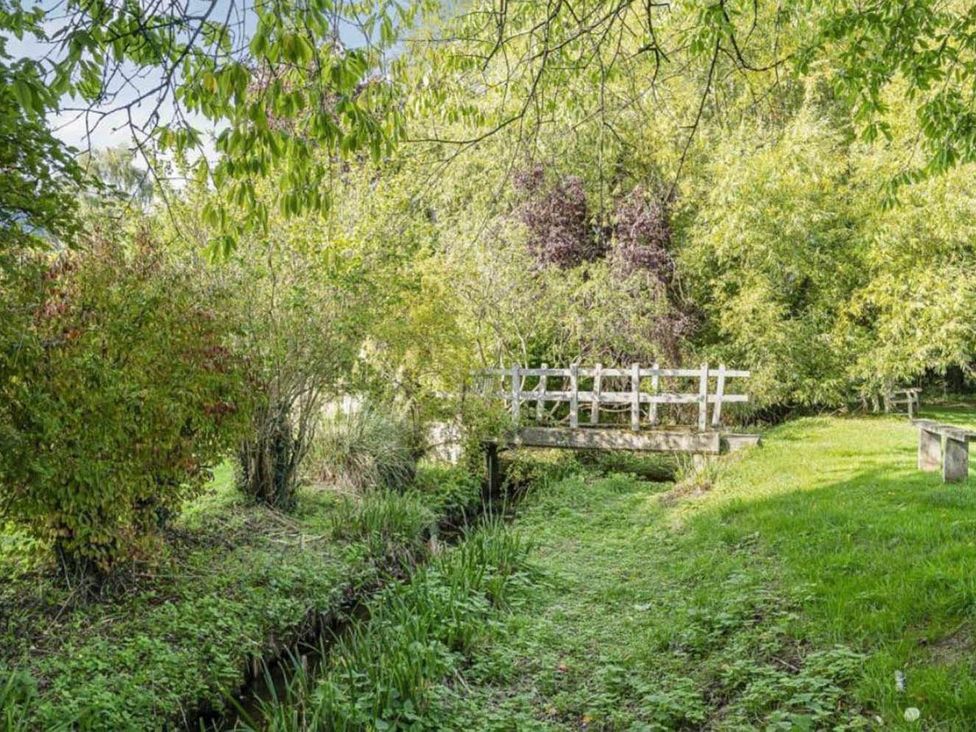 A garden with a bridge over a waterway at 17th Century Farmhouse Near Silverstone Circuit Tiffield