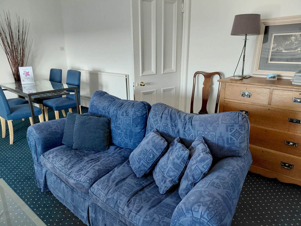 A living room with a blue sofa and dining area at Sleeps6 3Bed Ayrshire Coast Near Beach Prestwick