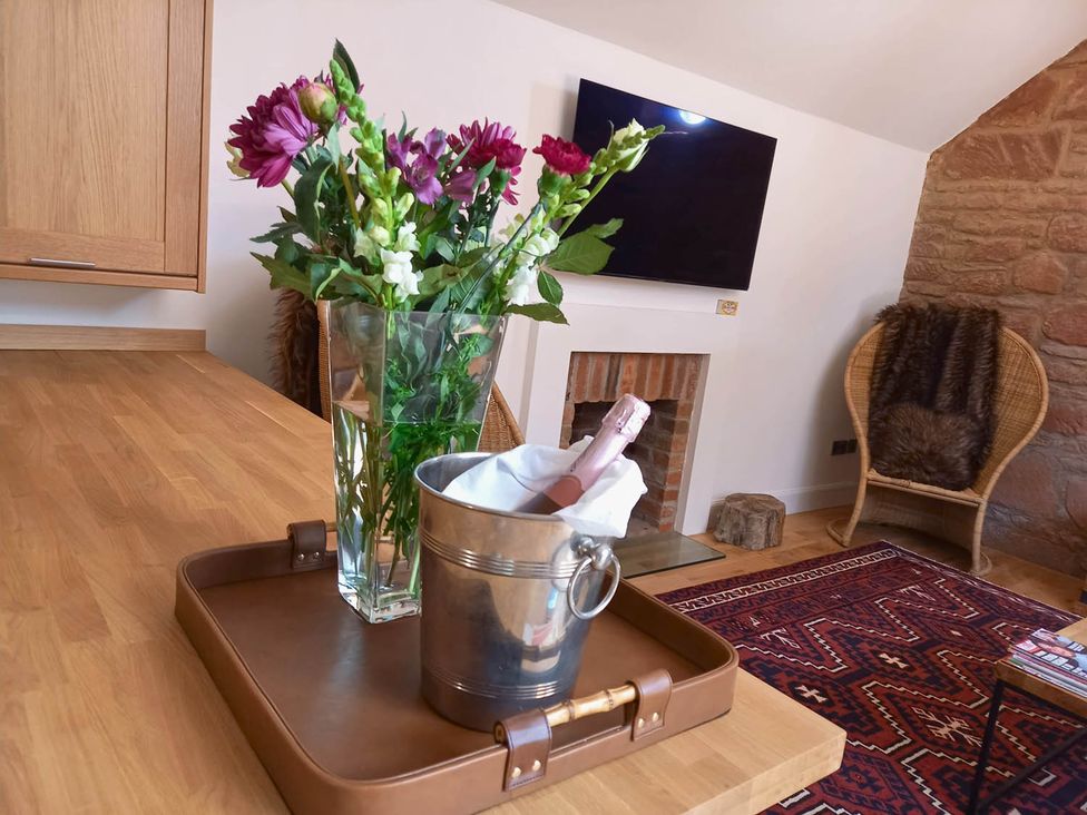 A living room with flowers in a vase and a wine bucket at Sleeps6 3Bed Ayrshire Coast Near Beach Prestwick