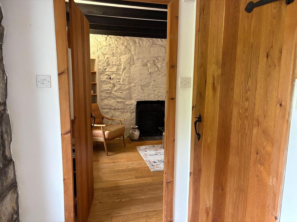 A sitting room with a chair and fireplace at Cosy Cottage Retreat in Edinbane