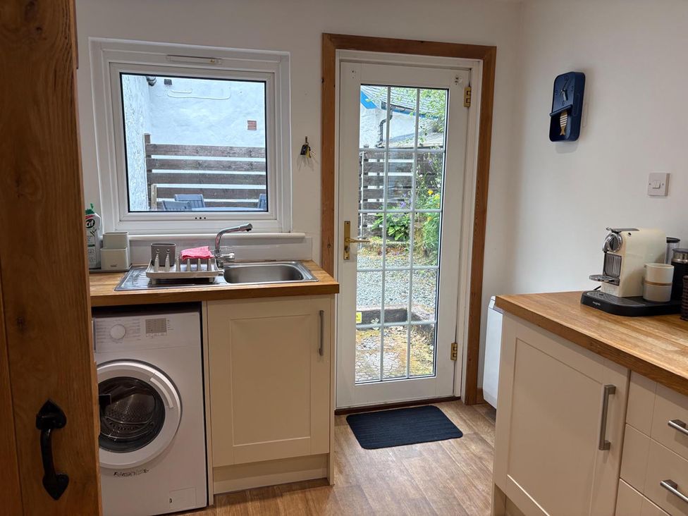 A kitchen with a washing machine and sink at Cosy Cottage Retreat in Edinbane