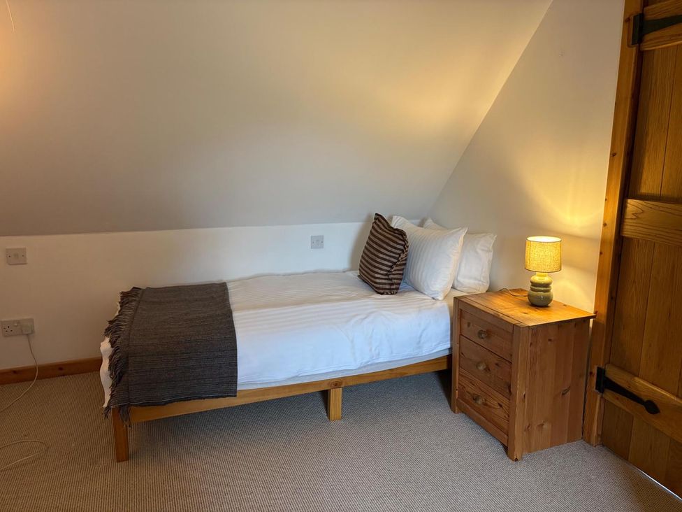 A bedroom with a single bed and bedside table at Cosy Cottage Retreat in Edinbane