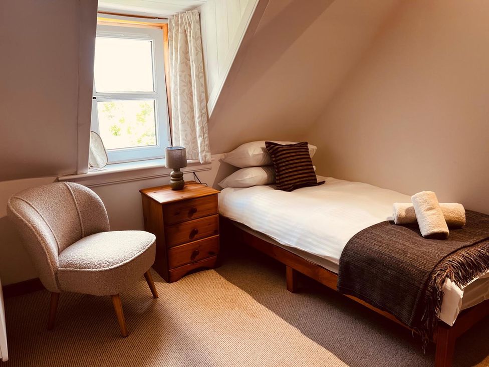 A bedroom with a bed and chair at Cosy Cottage Retreat in Edinbane