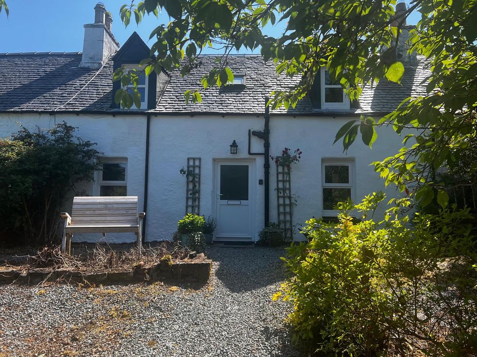 A house with a bench and gravel pathway at Cosy Cottage Retreat in Edinbane near Portree