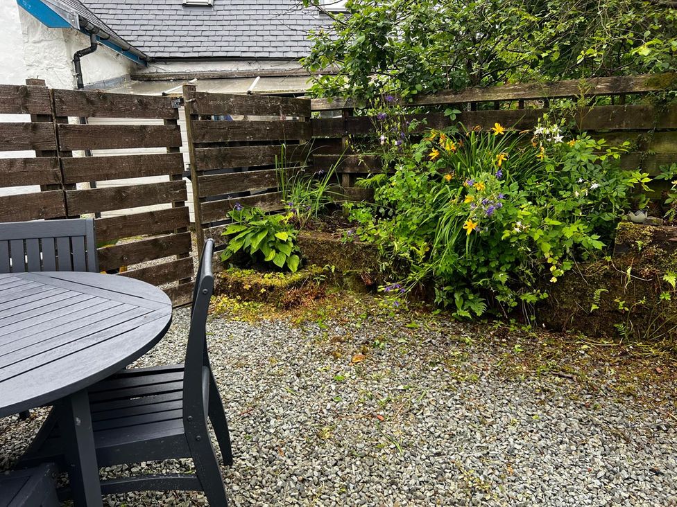 A garden with a table, chairs, plants and a gravel surface at Cosy Cottage Retreat in Edinbane
