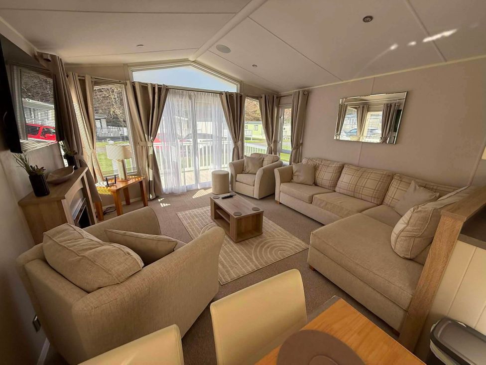A living room with a sofa, chairs, coffee table, and fireplace at 3 Bed Lodge Sleeps 6 Decking Parking WiFi Dunbar