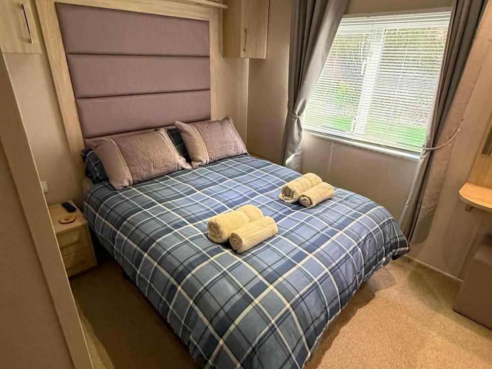 A bedroom with a bed, pillows, towels and a window at 3 Bed Lodge Sleeps 6 Decking Parking WiFi Dunbar