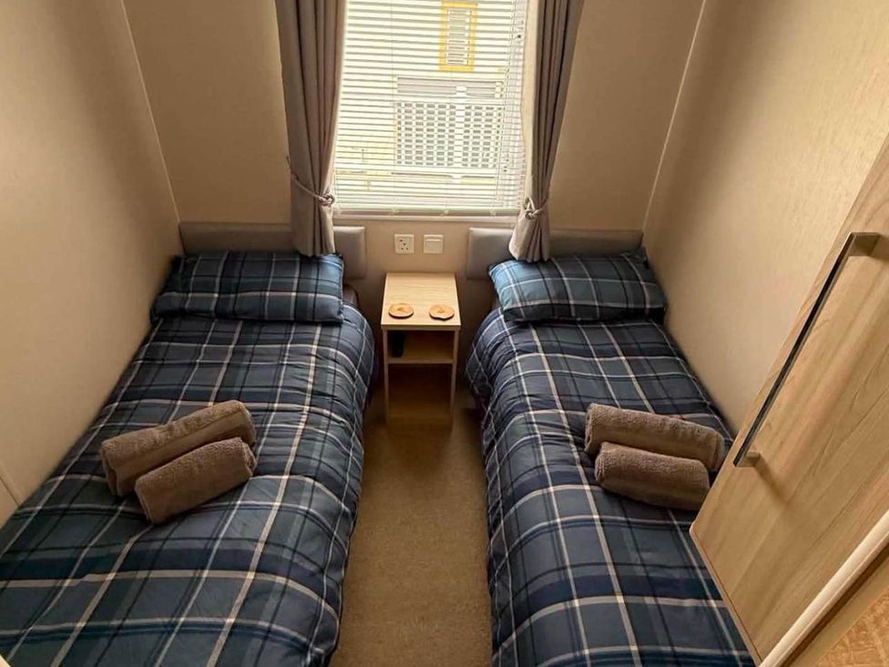 A bedroom with two single beds and a bedside table at 3 Bed Lodge Sleeps 6 Decking Parking WiFi Dunbar