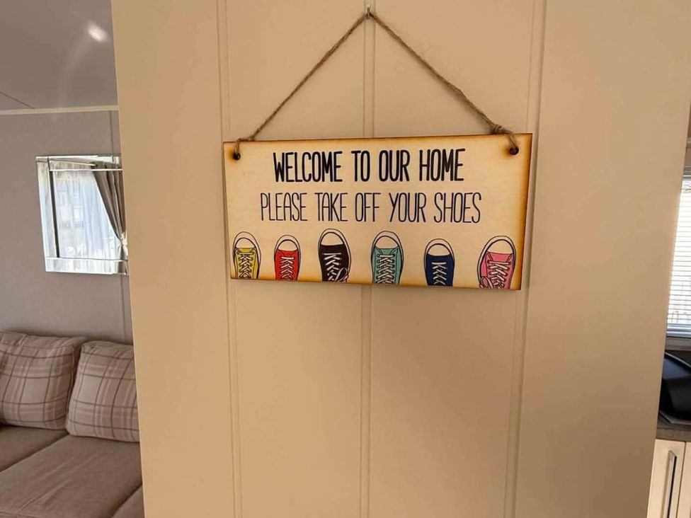 A sign on the wall requesting to take off shoes in a living room at 3 Bed Lodge Sleeps 6 Decking Parking WiFi, Dunbar