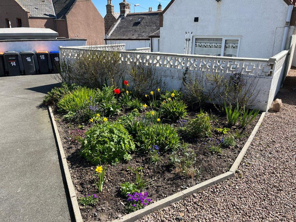 A garden with flowers and a decorative wall at Costal Cottage Boddam Sleeps6 Pet Friendly Boddam