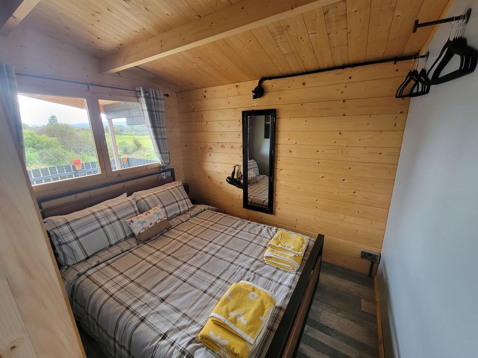 A bedroom with a bed and mirror at Fairvine Cabin Fort Augustus Mtn View Pet Friendly in Fort Augustus