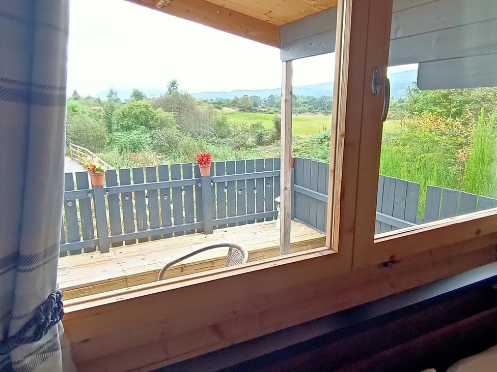 A view from a window showing a deck with a chair at Fairvine Cabin Fort Augustus Mtn View Pet Friendly in Fort Augustus