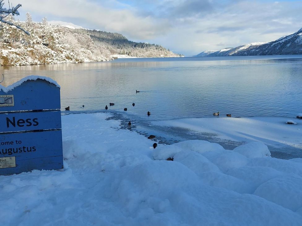 A lake with snowy shore and ducks at Fort Augustus