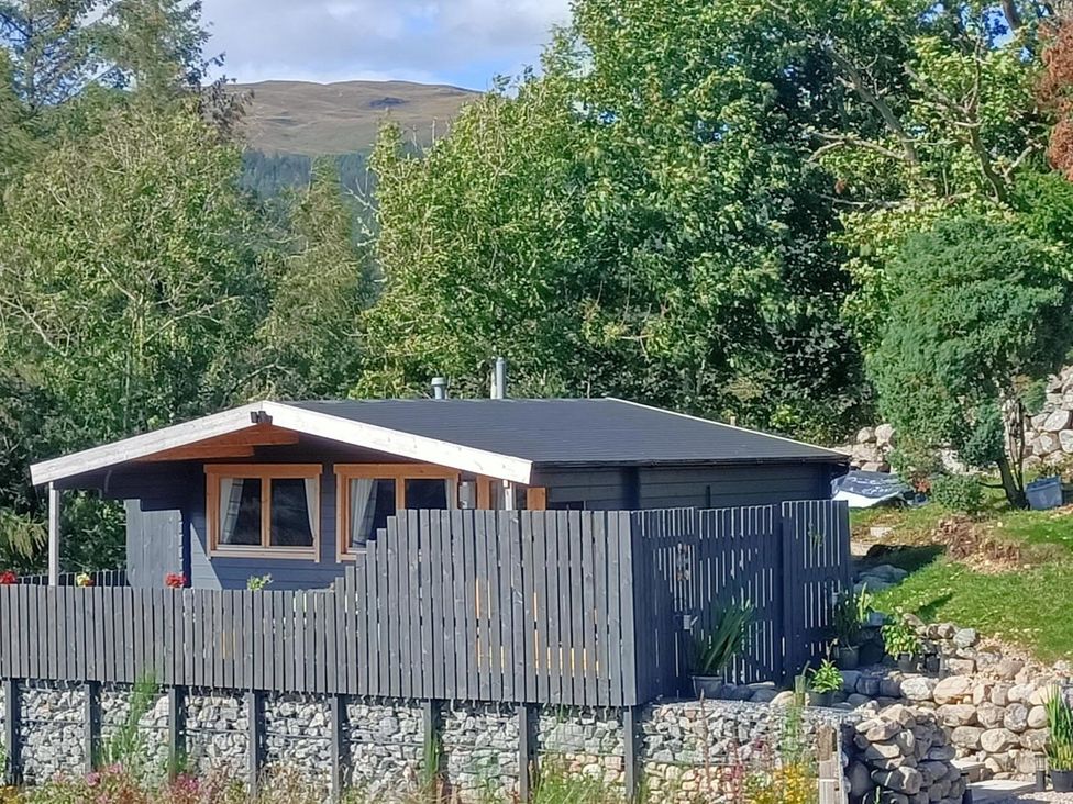 A cabin with a fence and stone wall at Fairvine Cabin Fort Augustus Mtn View Pet Friendly Fort Augustus