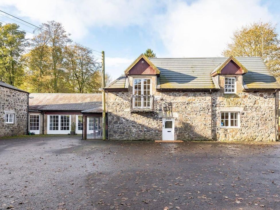 An outdoor view of a stone building with multiple windows and a driveway at Luxury Duplex Sleeps 2 Hot Tub Balcony Parking Duncrievie near Milnathort