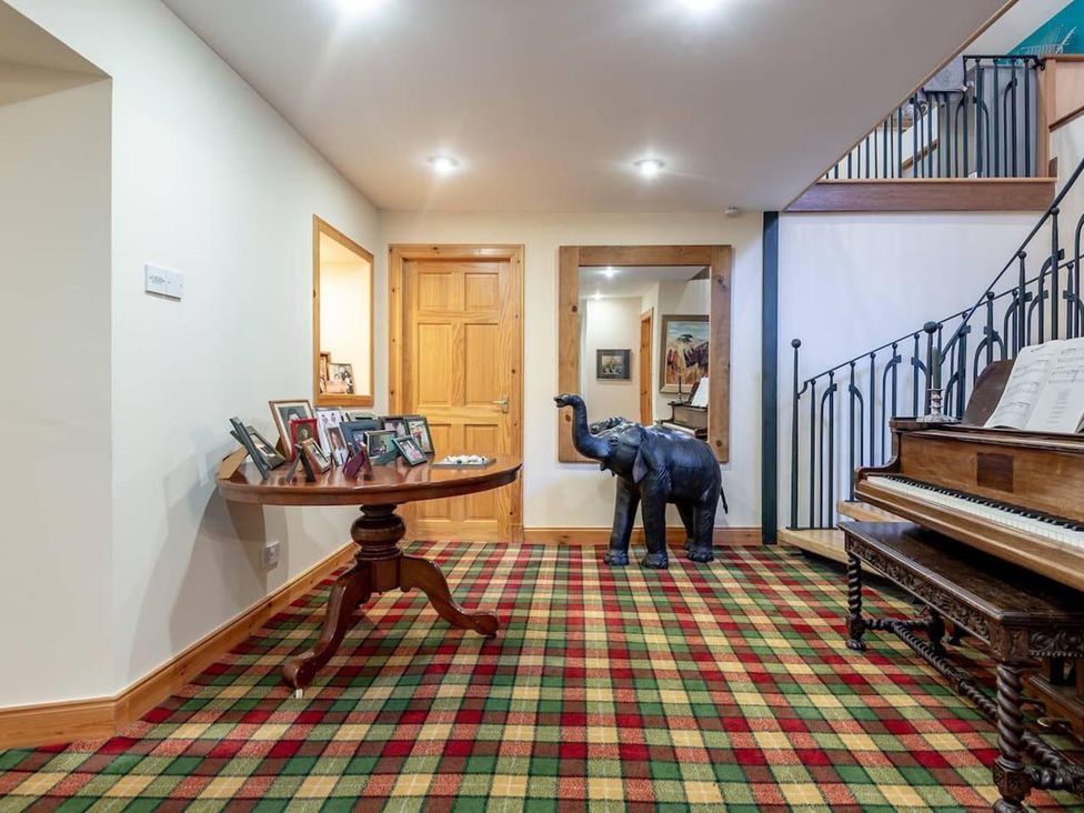 A hallway with a table and photo frames at Luxury Duplex Sleeps 2 Hot Tub Balcony Parking Duncrievie near Milnathort