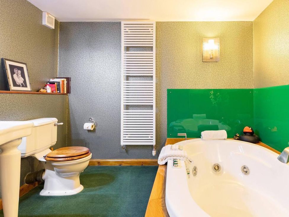 A bathroom with a bathtub, toilet and shelf at Luxury Duplex Sleeps 2 Hot Tub Balcony Parking in Duncrievie near Milnathort