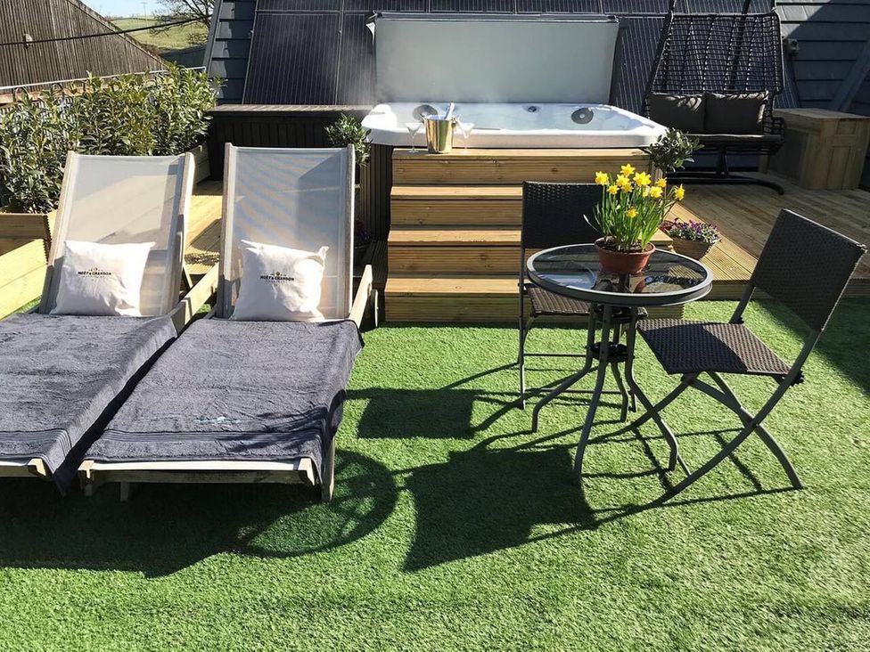 An outdoor area with lounge chairs and a hot tub at Luxury Duplex Sleeps 2 Hot Tub Balcony Parking in Duncrievie near Milnathort