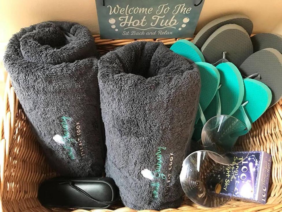 A basket with towels, flip flops, sunglasses, and a sign at Luxury Duplex Sleeps 2 Hot Tub Balcony Parking Duncrievie near Milnathort