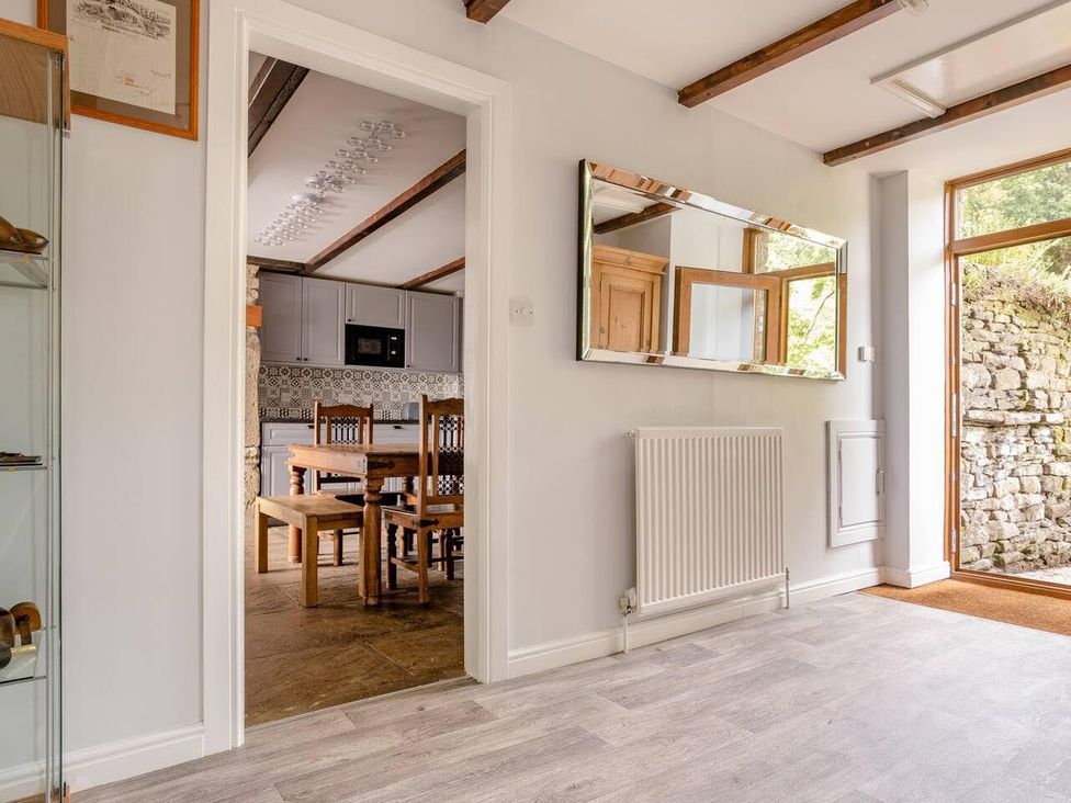 A hallway featuring a mirror, radiator, and a view into a kitchen at OldMill 2Bed Sleeps6 PrivateGarden OptionalHotTub, Oakworth